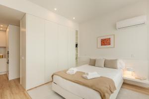 a white bedroom with a bed with two towels on it at Boavista Collection Ap for Family by Sé Apartamentos in Braga
