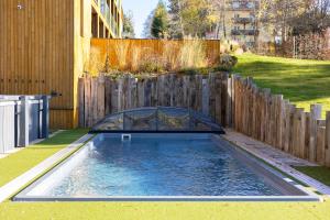 a swimming pool in a backyard with a wooden fence at JBX Resort Avenue Lipno in Lipno nad Vltavou