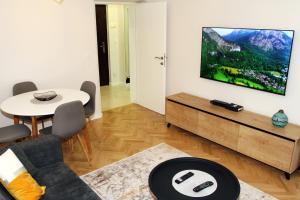 a living room with a couch and a tv on a wall at Apartment Bella in Sarajevo