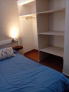 1 dormitorio con 1 cama azul y estanterías blancas en Dulcich Alojamiento en Merlo