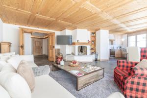 een woonkamer met witte meubels en een houten plafond bij St Moritz 3 Suite vista lago in St. Moritz
