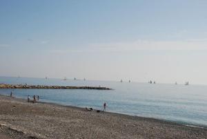 a group of people on a beach with boats in the water at Appartamento Margherita Trilocale ad Ospedaletti a pochi passi dal mare in Ospedaletti