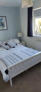 a large white bed in a bedroom with a window at Sea Crest, Beautiful home in Tenby with sea views in Pembrokeshire