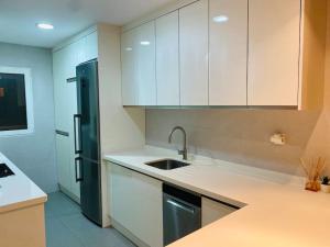 a kitchen with white cabinets and a black refrigerator at Apartamento centro de Granada 2 in Granada