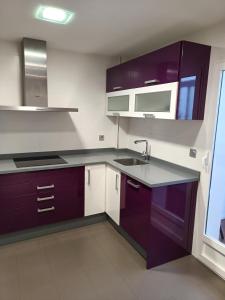 a kitchen with purple cabinets and a sink at Habitación privada en casa particular in Albacete