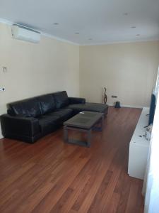 Sala de estar con sofá negro y mesa de centro en Habitación privada en casa particular en Albacete