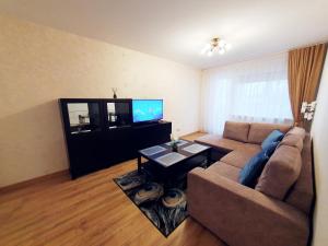 a living room with a couch and a tv at Dainai 1-Bedroom apartament. in Šiauliai