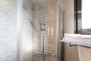 baño con ducha y puerta de cristal en Hotel Can Pamplona, en Vic