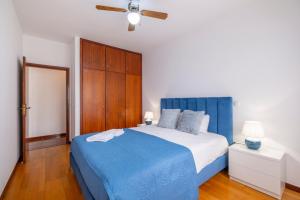 1 dormitorio con 1 cama azul y armario de madera en Sol&mar, en Ponta do Sol