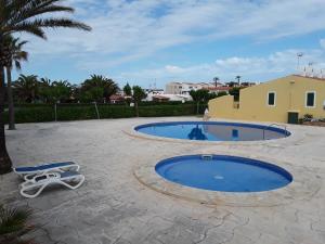 una piscina con un par de sillones junto a ella en Apartamento en Calan Blanes, Ciutadella en Cala en Blanes