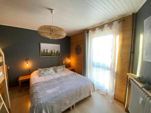 Un dormitorio con una cama y una ventana grande. en Appartement cosy au pied des pistes, en La Clusaz
