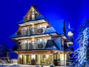 a house in the snow at night at Villa Taternik by Golden Apartments in Zakopane