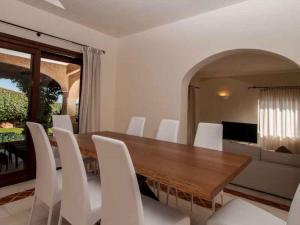 アッビアドリにあるHoliday home in Arzachena 31407のダイニングルーム(木製テーブル、白い椅子付)