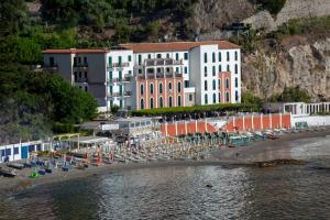 a large building with chairs and umbrellas on a beach at Hotel Lido Mediterranee in Taormina