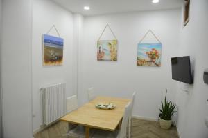 a dining room with a wooden table and paintings on the wall at Salifornia casa vacanze in Salerno