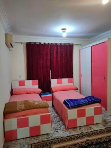 2 camas en una habitación con rojo y blanco en Lojii, en El Cairo