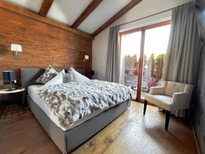 a bedroom with a bed and a chair and a window at HIDEAWAY DESIGN CHALET by Belle Stay in Kitzbühel