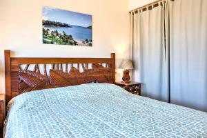 um quarto com uma cama azul e uma janela em Pristine Lihue Condo with Balcony Walk to Beach! em Lihue