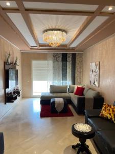 een woonkamer met een bank en een kroonluchter bij Big luxury apartment near airport in Nouaceur