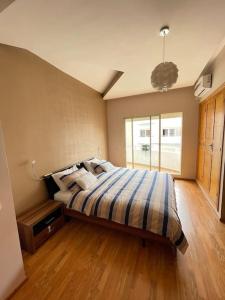 a bedroom with a bed with a striped comforter at Big luxury apartment near airport in Nouaceur