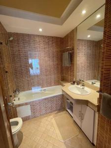 een badkamer met een bad, een wastafel en een toilet bij Big luxury apartment near airport in Nouaceur