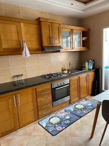 a kitchen with wooden cabinets and a stove top oven at Big luxury apartment near airport in Nouaceur