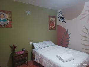 Casa de Claudia y Hugo في مدينة أواكساكا: غرفة نوم بسرير وطاولة مع موقف ليلي