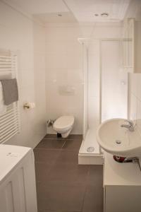 Baño blanco con aseo y lavamanos en Innsbruck City Center Studio I 24h self-check-in, en Innsbruck