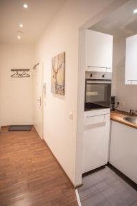 uma cozinha com paredes brancas e pisos em madeira em Innsbruck City Center Studio I 24h self-check-in em Innsbruck
