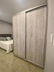 Una puerta corredera de cristal en un dormitorio con cama en PEDROSAS Departamentos en Villa Elisa