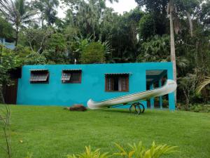 a blue house with a surfboard in front of it at Recanto das Palmeiras Praia da Longa in Angra dos Reis