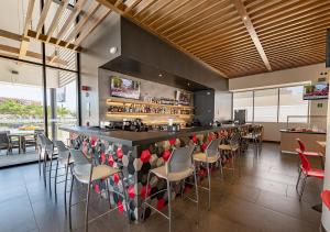 um restaurante com um bar com cadeiras e mesas em Ramada Encore by Wyndham Guadalajara Aeropuerto em Guadalajara