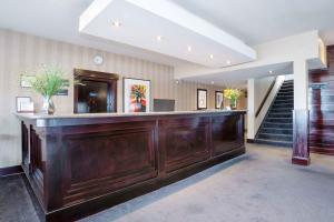 a lobby with a large wooden bar with a staircase at Sandman Hotel Cranbrook in Cranbrook