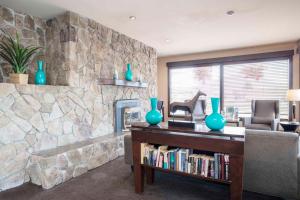 a living room with a stone fireplace and a book shelf at Sandman Hotel Cranbrook in Cranbrook