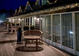 a wooden deck with a bench on a balcony at night at Yare View Holiday Cottages in Brundall