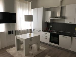 una cucina con armadi bianchi e tavolo bianco di Appartamento Il Gelsomino a Castelleone