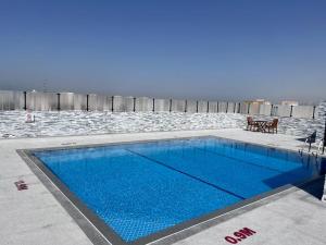 a swimming pool with blue water in front of the ocean at Studio Deira naif in Dubai