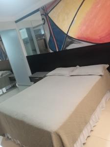 uma cama num quarto com uma pintura na parede em Studio Maraba-LOFT LINDO em Marabá