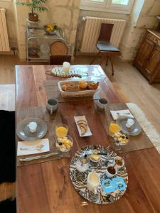 een houten tafel met eten erop bij Suite privative Abella - Aile de maison bourgeoise in Ambarès-et-Lagrave