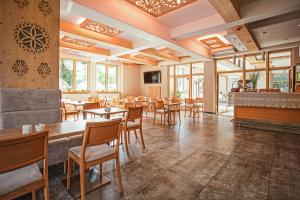 un restaurante con mesas, sillas y ventanas en Villa Cannes Resort Zakopane - grota solna, sauna fińska en Zakopane
