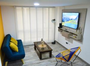 un soggiorno con un divano blu e una TV di Espectacular Apto Zona Rosa - Milán Estrato 5 a Manizales