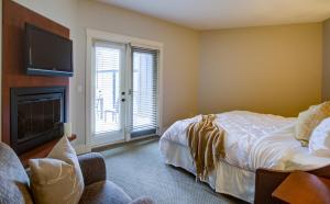 a bedroom with a bed and a flat screen tv at Misty Mountain- Premium 2 Bedroom Mountain View in Canmore