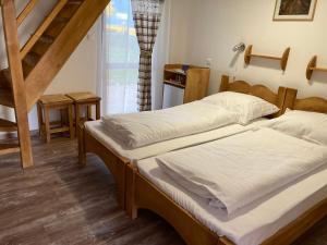 two twin beds in a room with a staircase at Székelyudvar Fogadó in Lukácsháza