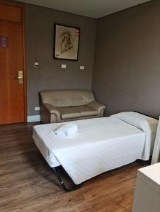 Pokój hotelowy z 2 łóżkami i krzesłem w obiekcie San Juan Royal w mieście Kurytyba