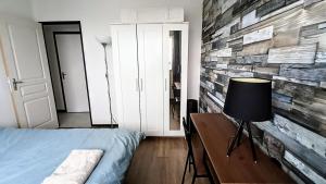 sypialnia z ceglaną ścianą, łóżkiem i lampą w obiekcie Logement entier proche de Lyon w mieście Vénissieux