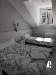 a hotel room with two beds and a window at Hostal San Pedro in Coslada