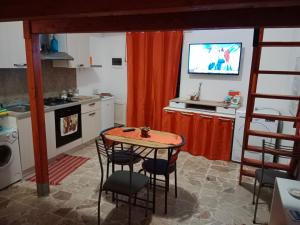 kuchnia ze stołem i krzesłami oraz telewizorem w obiekcie Casa dell'aquila Barocca w mieście Ragusa
