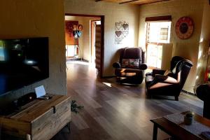 een woonkamer met lederen stoelen en een flatscreen-tv bij Cottage K'Gari in Franschhoek