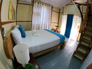 a bedroom with a bed with blue pillows and a staircase at Rustic House Punta Rucia in Punta Rucia