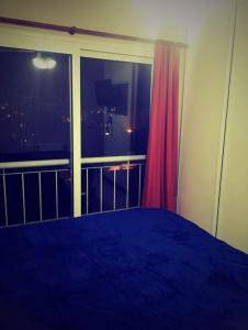 1 dormitorio con ventana grande y cama azul en Azucena Apart en Salta